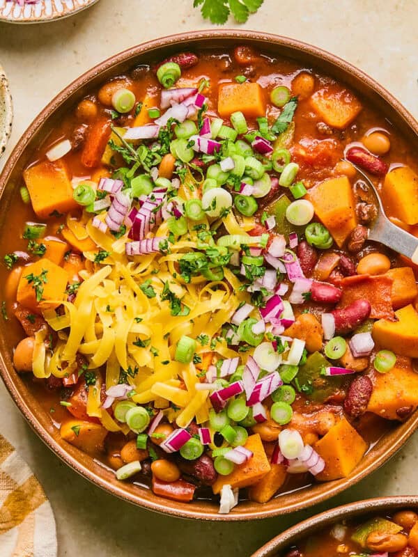 Overhead view of bowl with butternut squash chili with spoon scooping into the bowl.