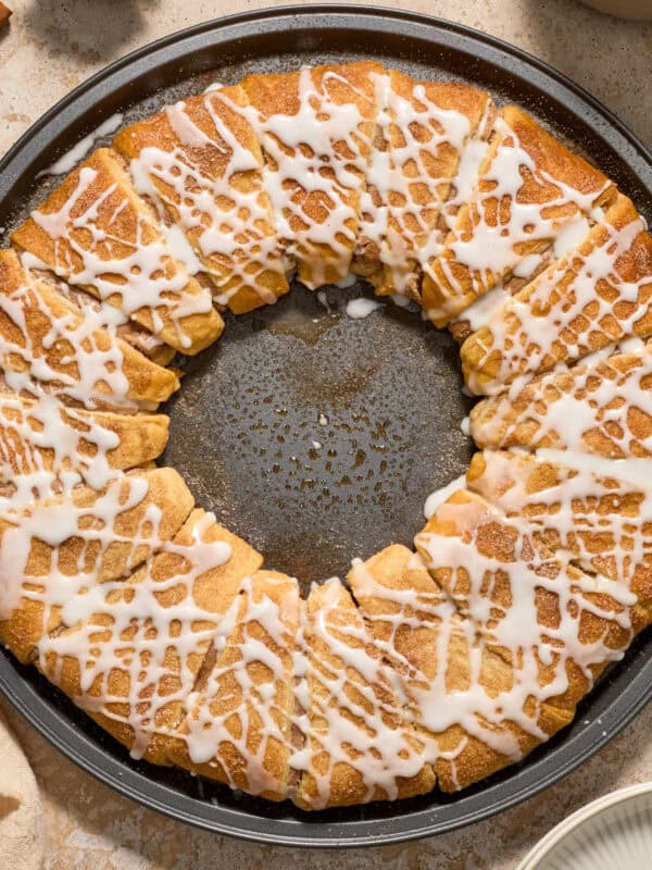 Cinnamon crescent wreath on pan with icing drizzle over top.