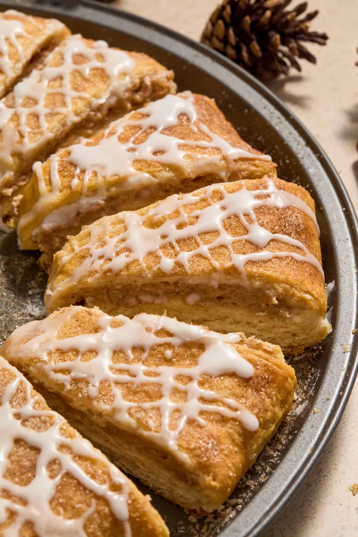 Slices of crescent roll wreath on pan with icing drizzle and cinnamon cream cheese filling.