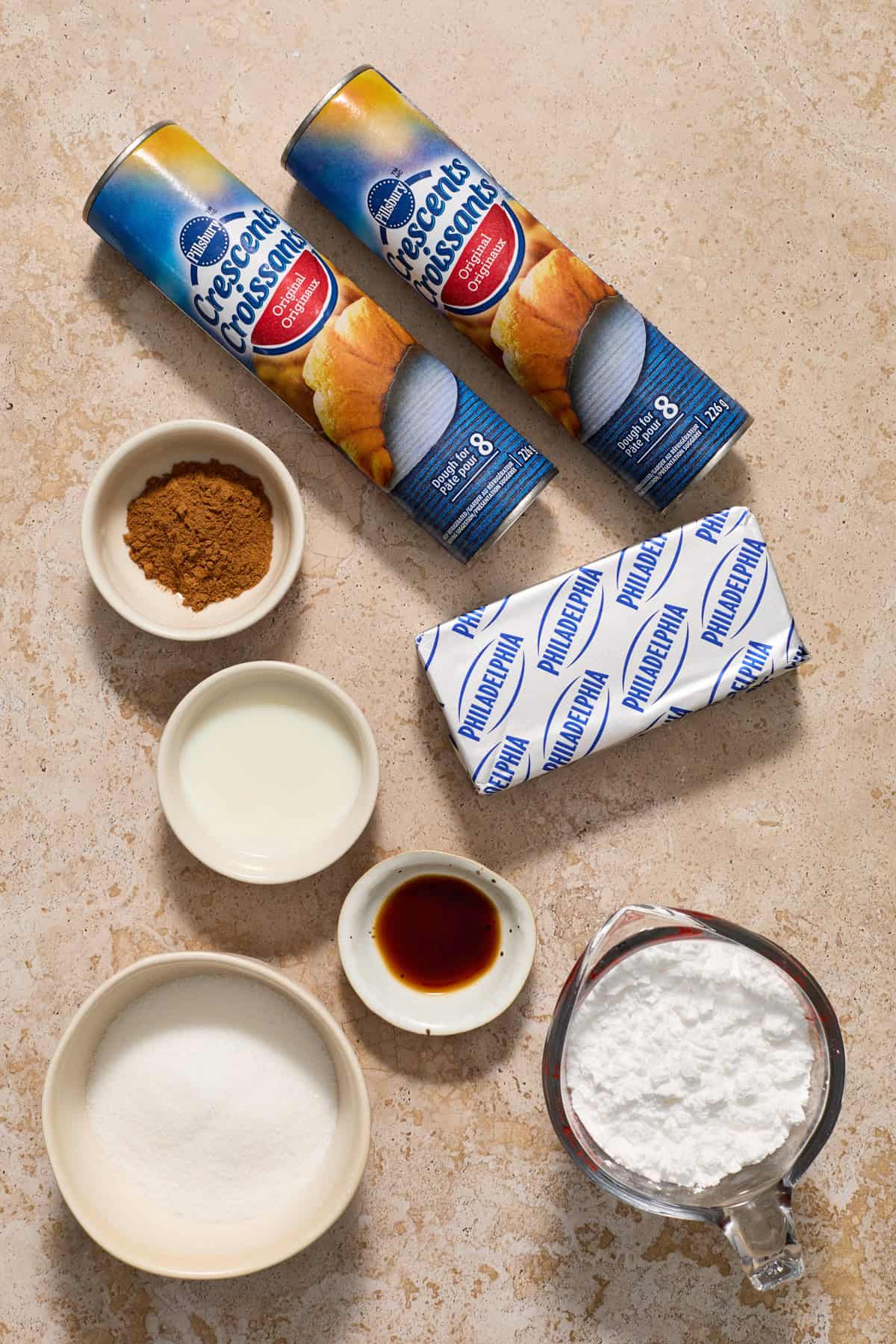 Ingredients on surface crescents, powdered sugar, cream cheese and more.
