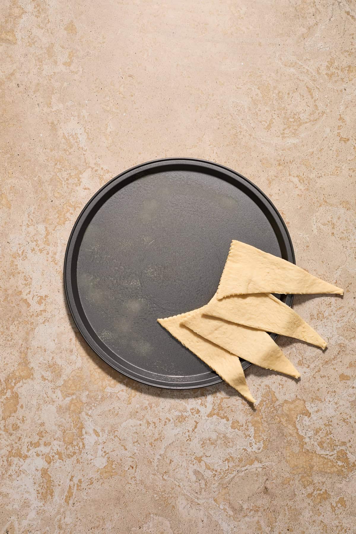 Crescent dough lined to start forming a circle on a pizza pan.