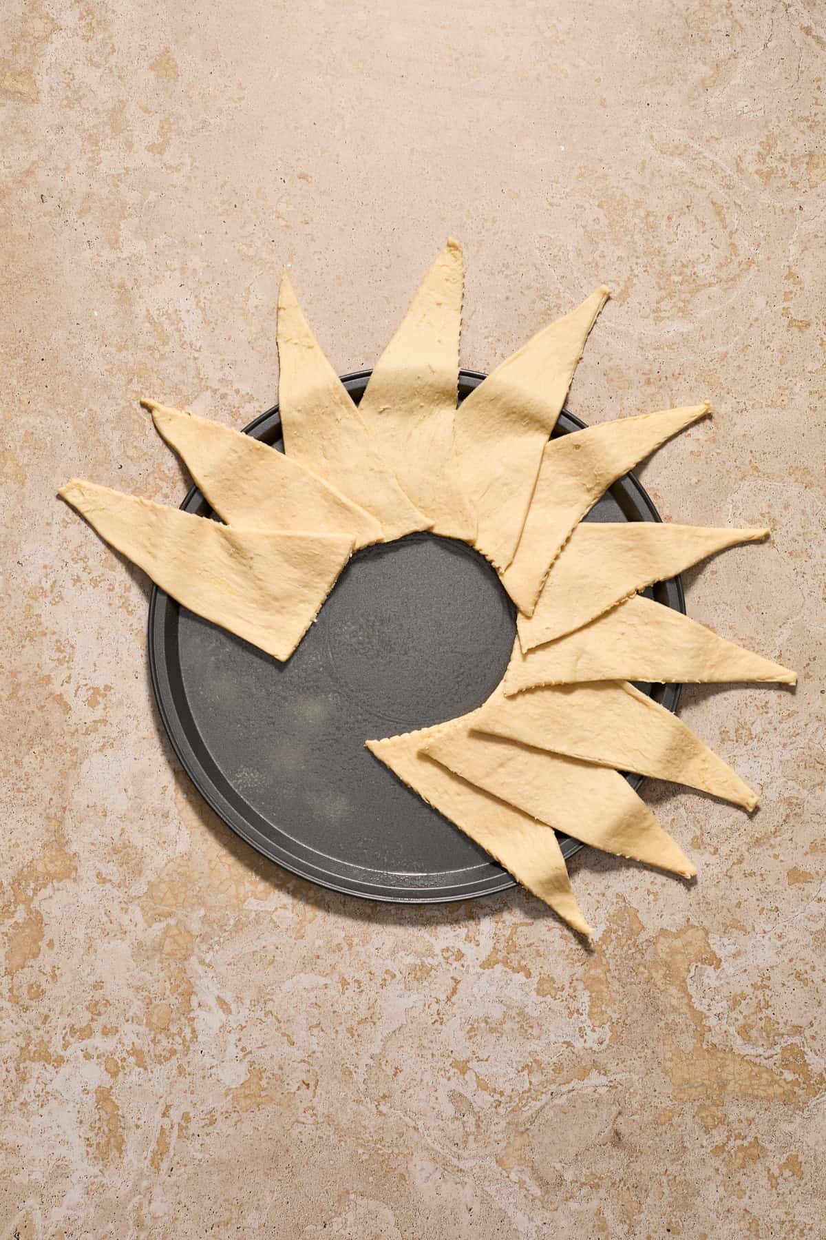 Crescent dough lined over halfway around a pizza pan to form a circular wreath shape.