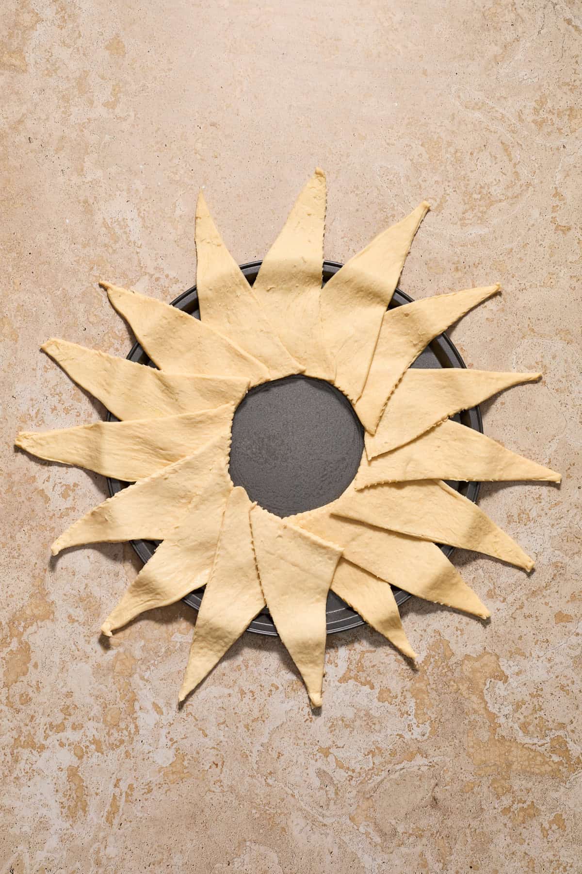 Crescent roll triangles arranged around a circular pan to form a full circle.