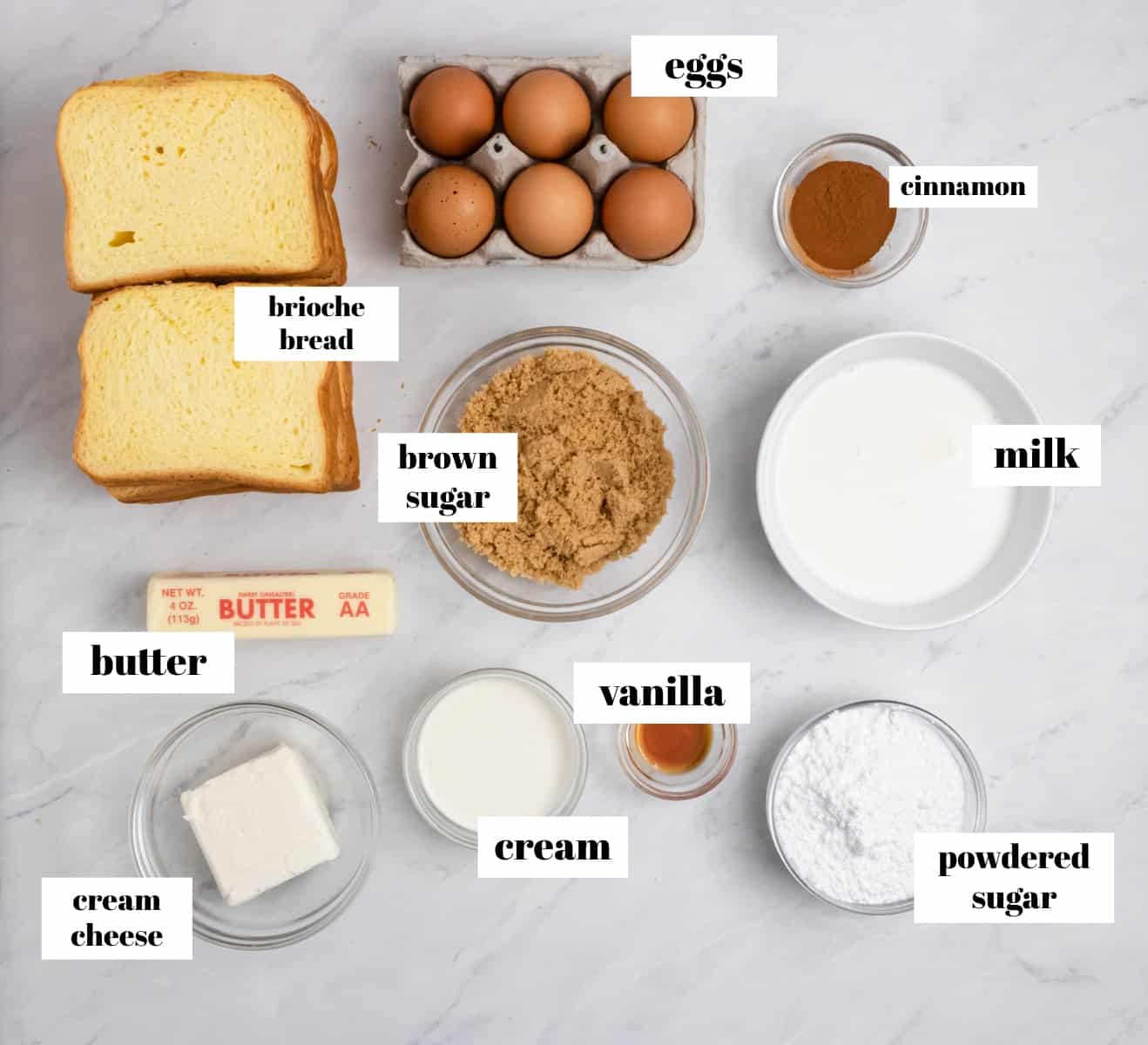 Brioche bread, eggs, milk, cream and other ingredients on counter.