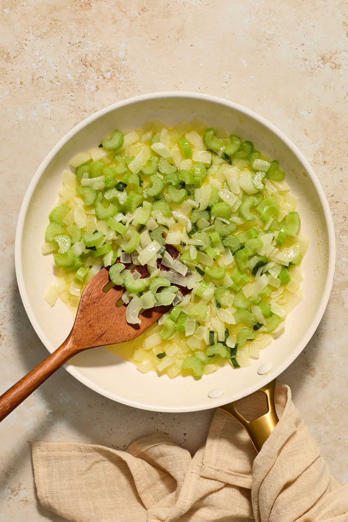 Sautéed onion and celery in butter with herbs and wooden spatula. 