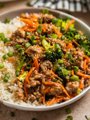 Turkey stir fry served with rice and topped with sesame seeds and green onion.