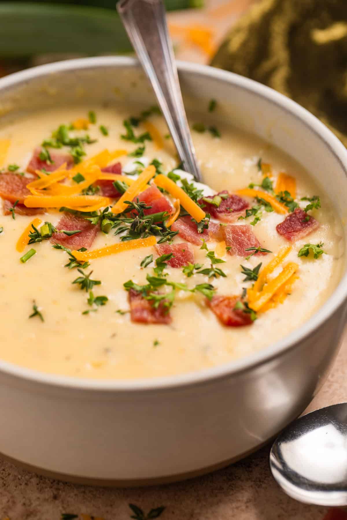 Bowl of Instant Pot Potato Leek soup topped with cheese, bacon, chives and fresh thyme.