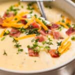 Bowl with soup topped with thyme, bacon, chives and cheese.