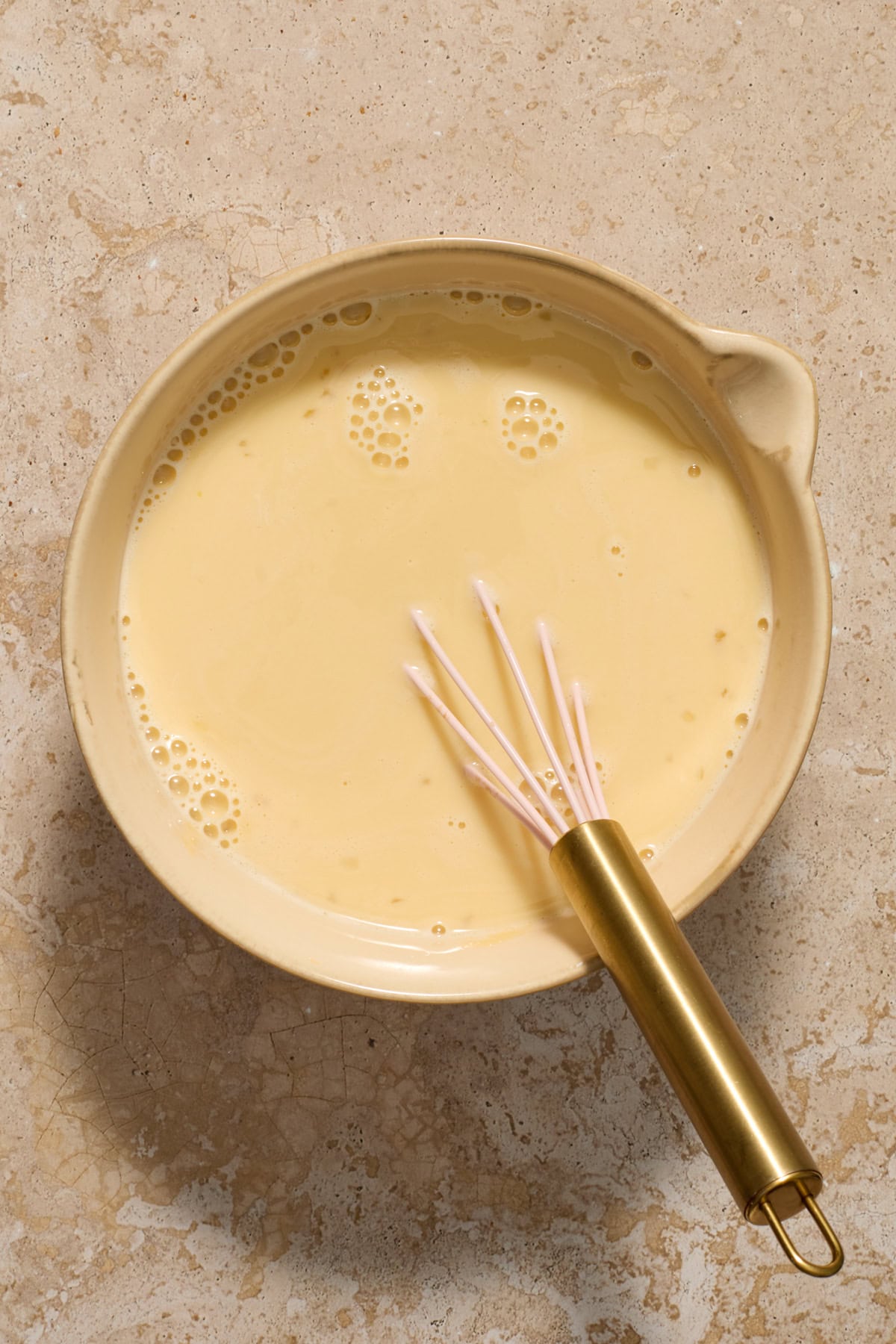 Egg mixture in bowl with whisk.