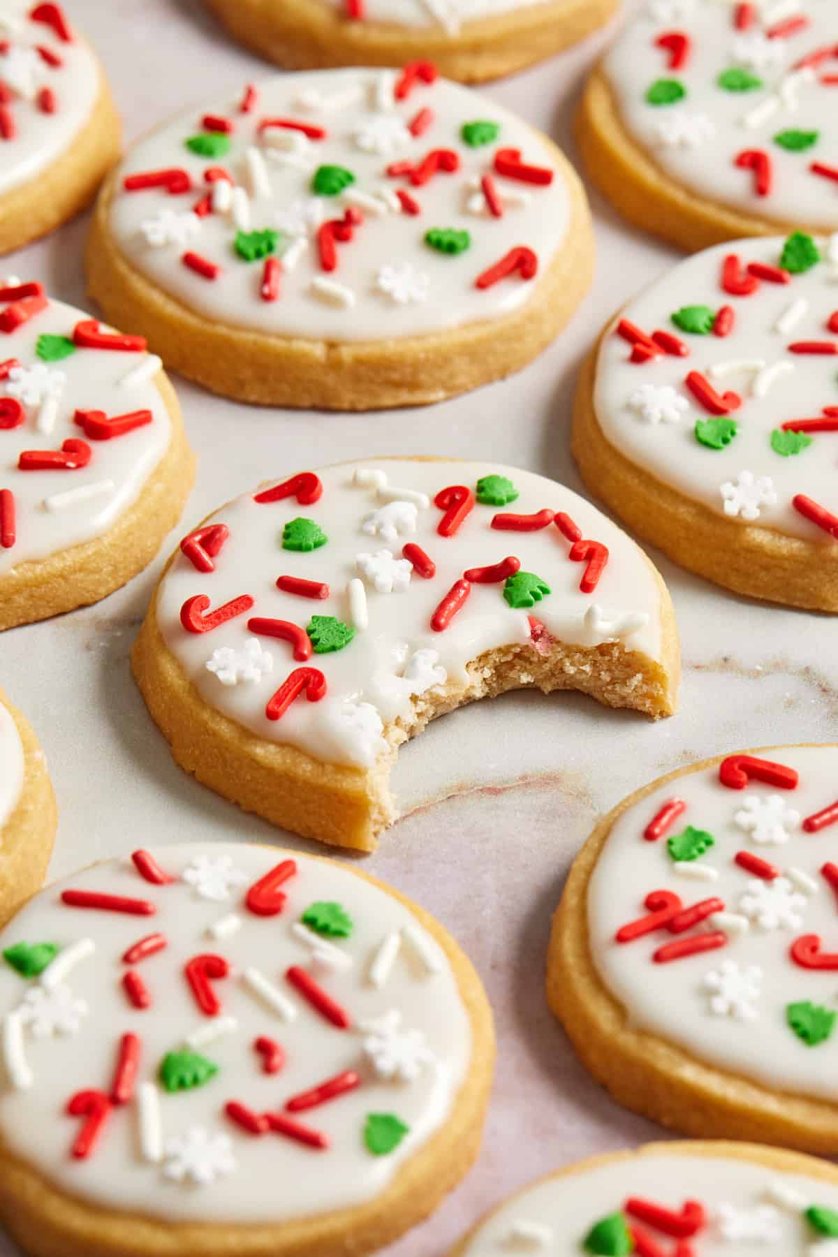 Christmas iced cookies arranged on surface with bite taken out of center cookie.