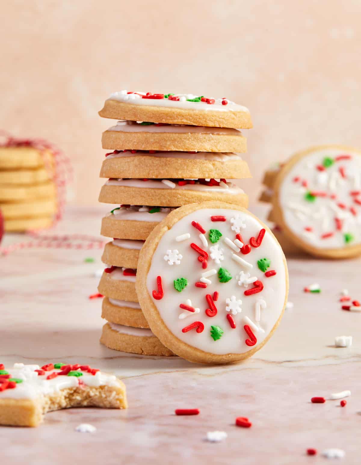 Stack of iced brown sugar Christmas shortbread cookies with one cookie propped up against the stack.