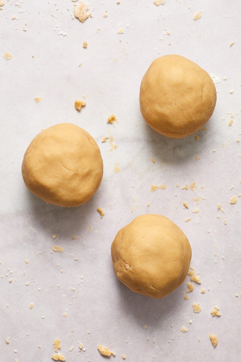 3 smooth balls of brown sugar shortbread cookie dough on floured surface.