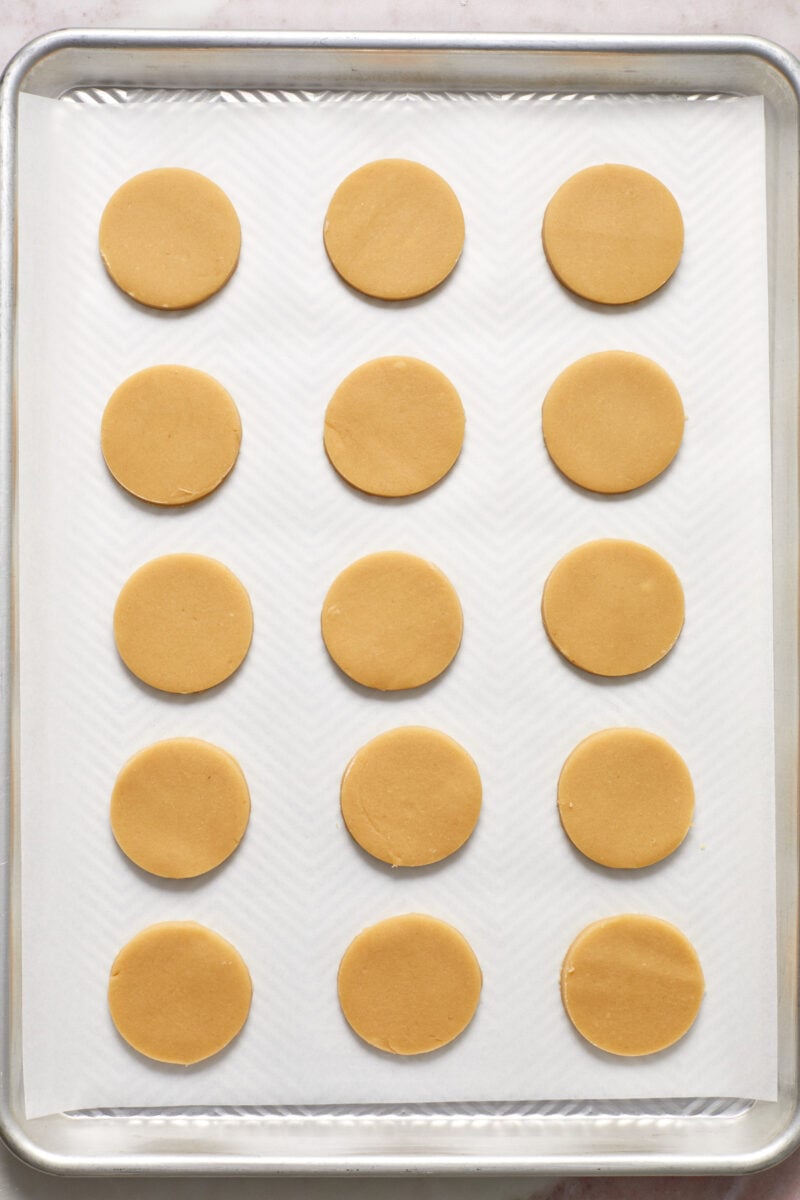 Cookie cutouts lined on parchment lined baking sheet.