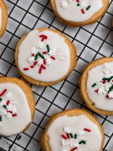 Christmas shortbread cookies with icing on cooling rack.