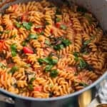 Stock pot with creamy tomato sauce and topped with herbs.