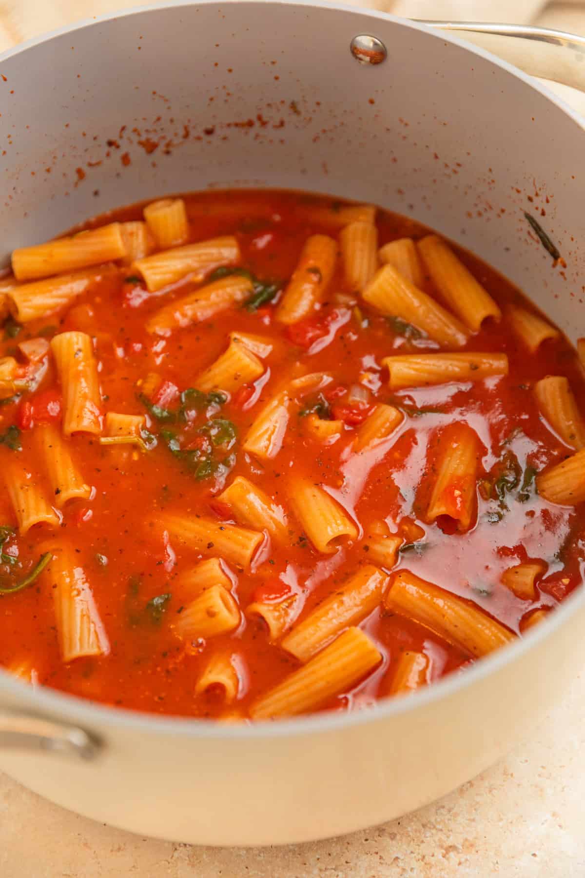 Pot with boiled pasta in sauce.
