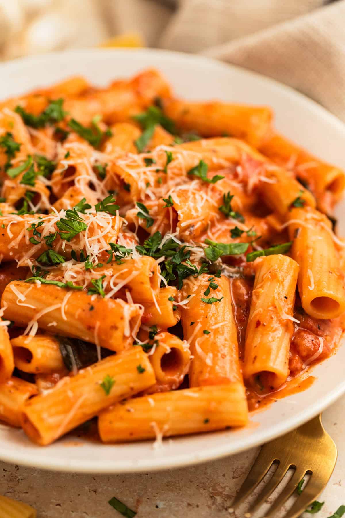 Plate with creamy one pot pasta topped with grated parmesan cheese, basil and parsley.