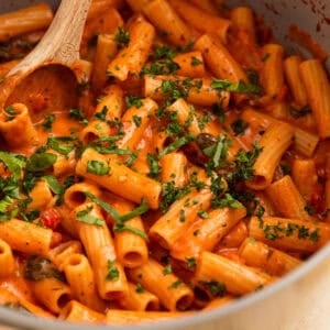 Creamy one pot tomato pasta in pot with wooden spoon.