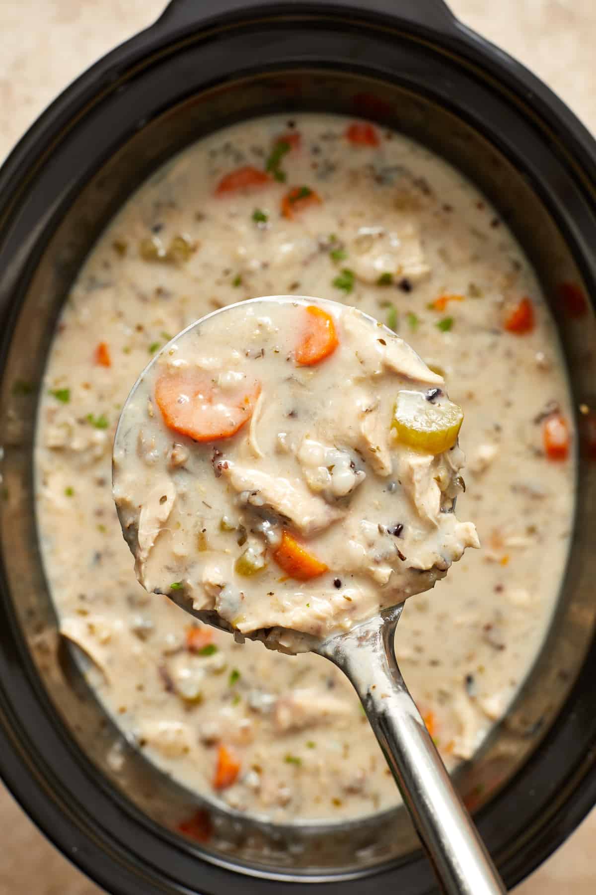 Close up view of crock pot chicken wild rice soup in ladle.