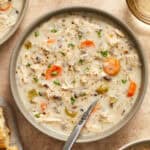 Creamy crockpot chicken wild rice soup in bowl with spoon and chopped parsley on top.
