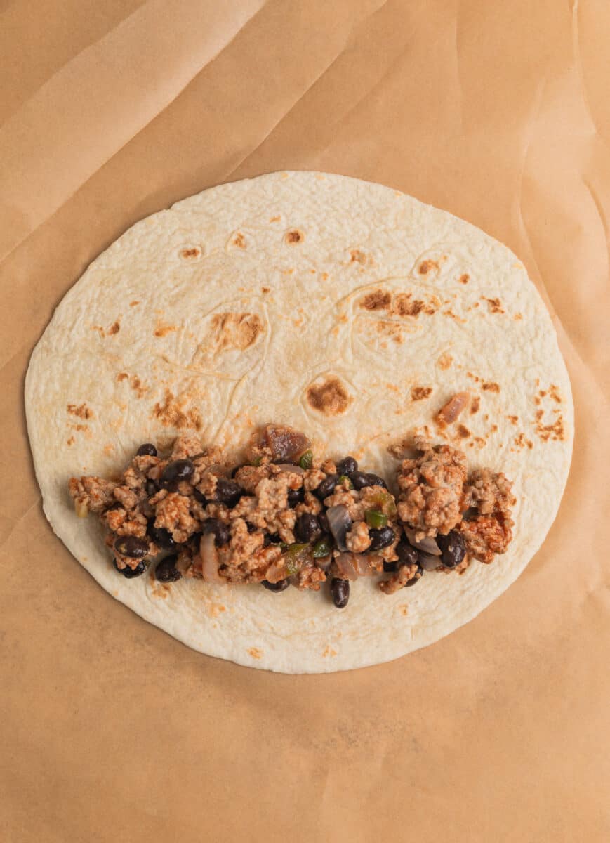 Ground turkey and black bean mixture spooned into tortilla.