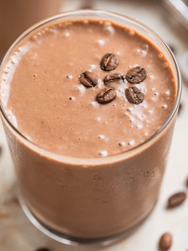 Peanut butter coffee smoothie in glass with coffee beans on top.