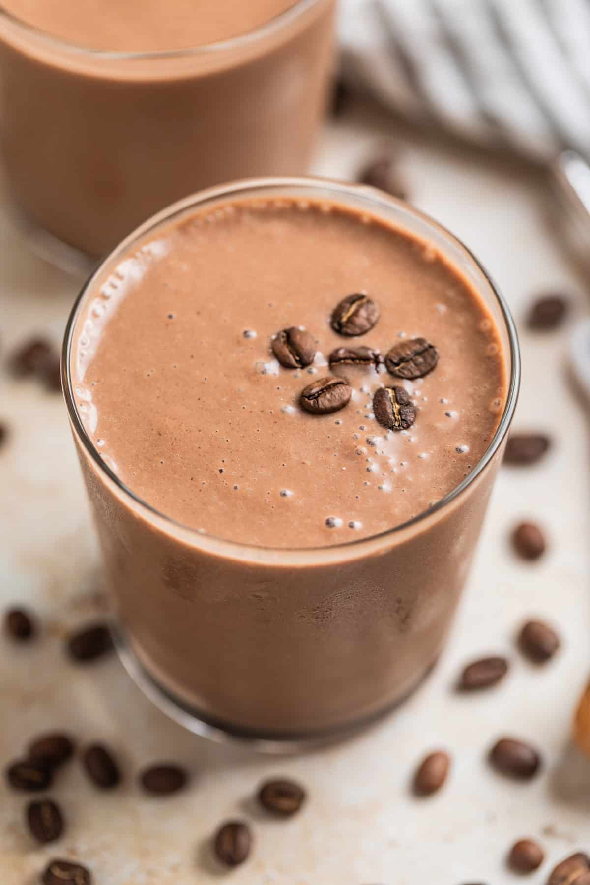 Peanut butter coffee smoothie in glass topped with coffee beans.