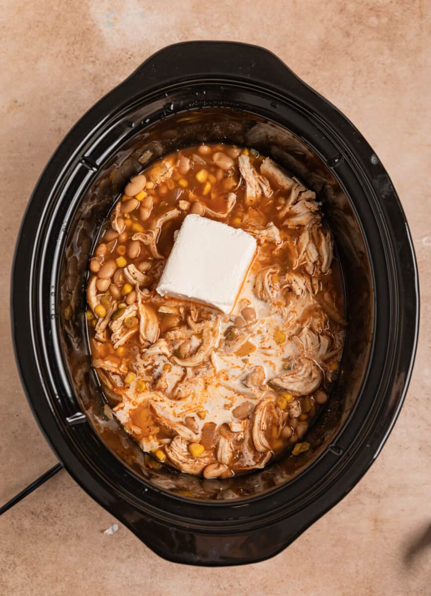 Cream cheese block added to crock pot with white chicken chili.