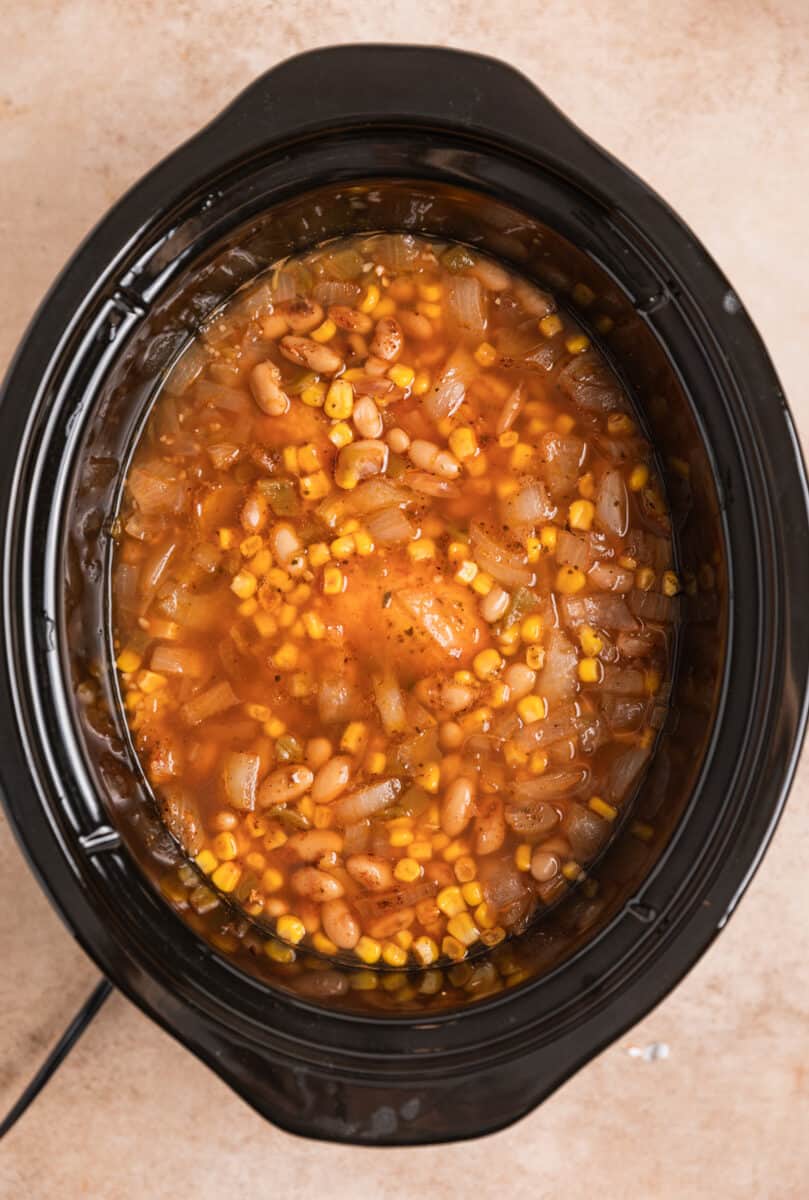 Cooked chicken chili in crockpot before chicken is shredded.