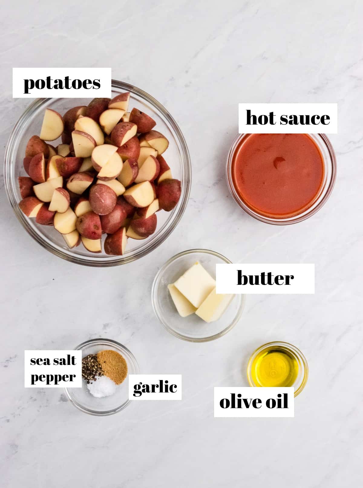 Baby potatoes, hot sauce, butter and other ingredients on counter.