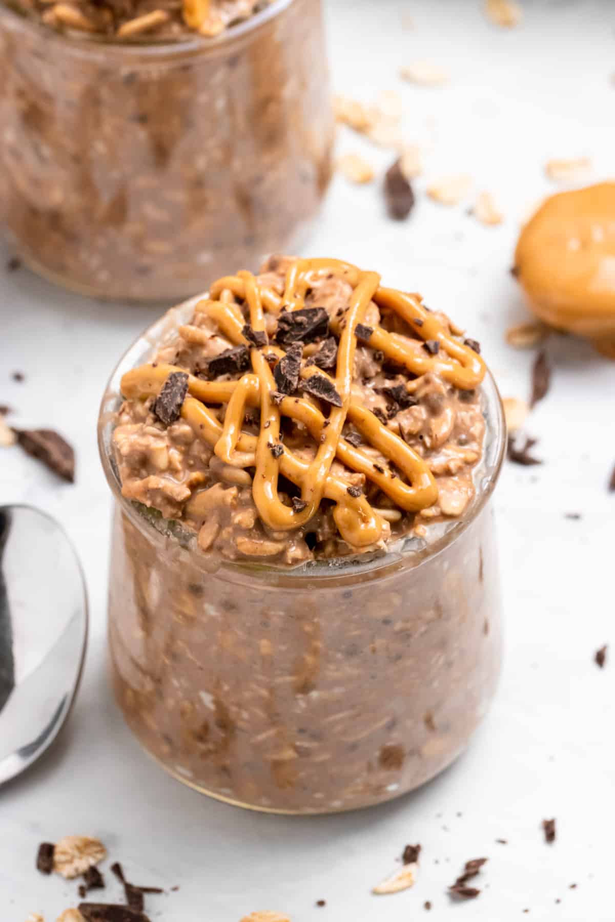 Peanut butter chocolate overnight oats in jar with peanut butter drizzle and chopped chocolate.