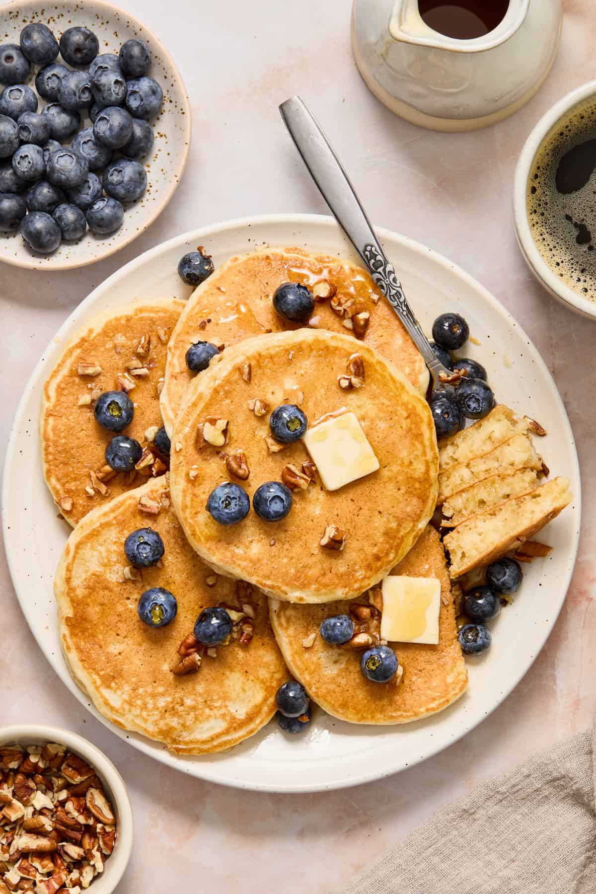 Plate with extra thick and fluffy pancakes with fork holding cut pancake pieces.