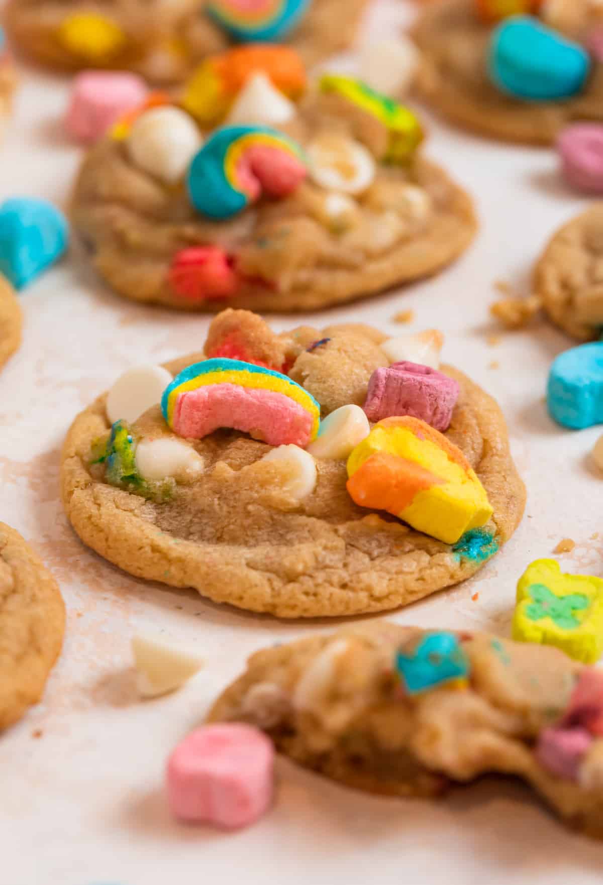 Lucky Charms cookies lined on counter with marshmallows and chocolate chips surrounding.