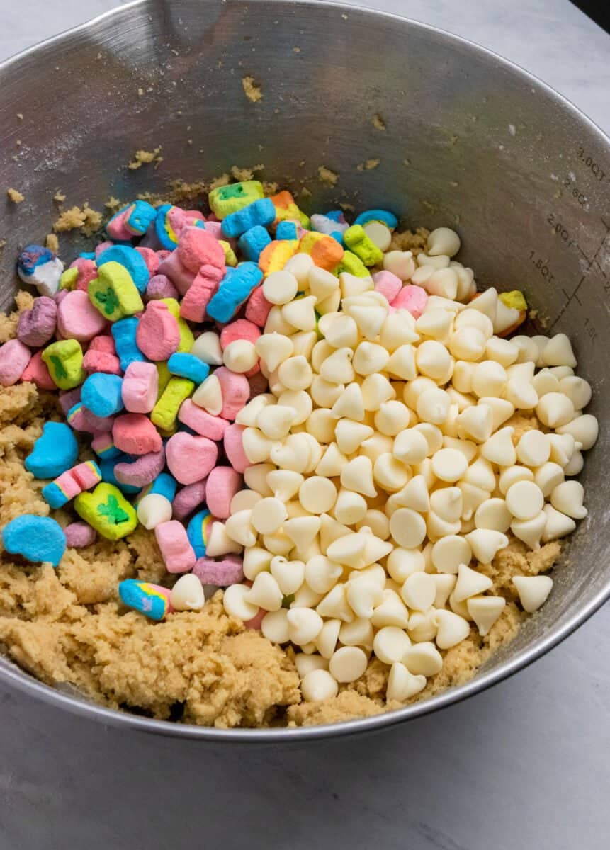 White chocolate chips and mini marshmallows added to cookie dough mixing bowl.