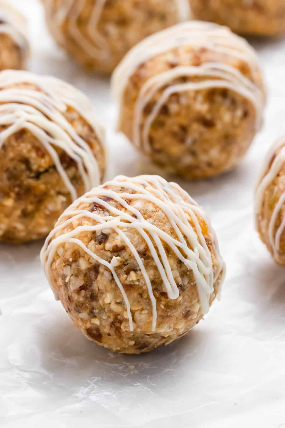 Energy bites on parchment with white chocolate drizzle.