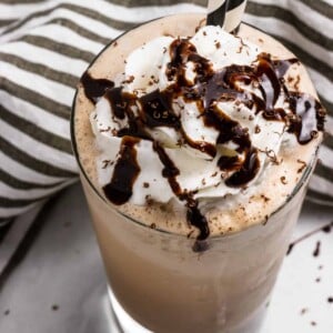 Mocha Frappuccino in glass with whipped cream and chocolate drizzle.