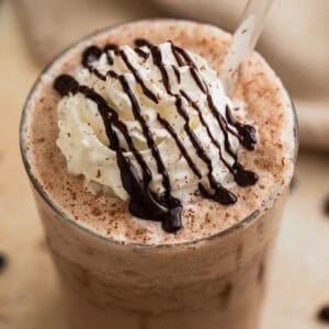 Mocha frappuccino iced coffee drink in glass with whipped cream and chocolate shavings.