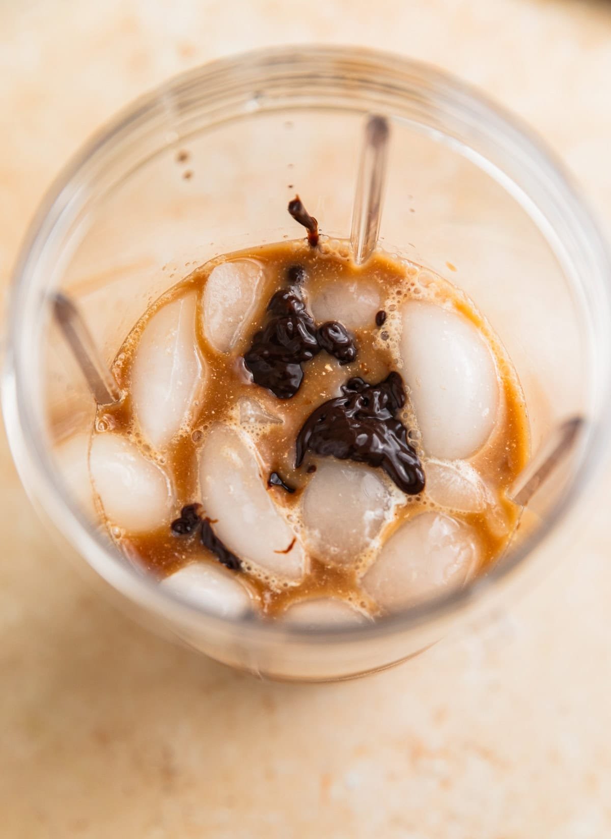 Ice, coffee, chocolate sauce and milk in blender before blending.