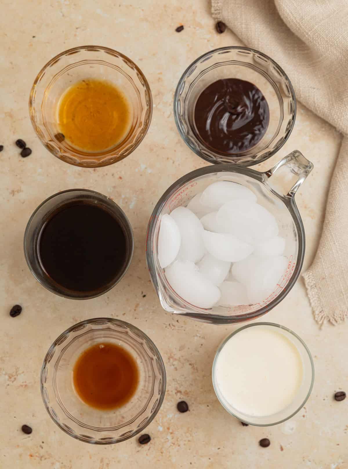 Ice, vanilla, coffee and other ingredients on surface.