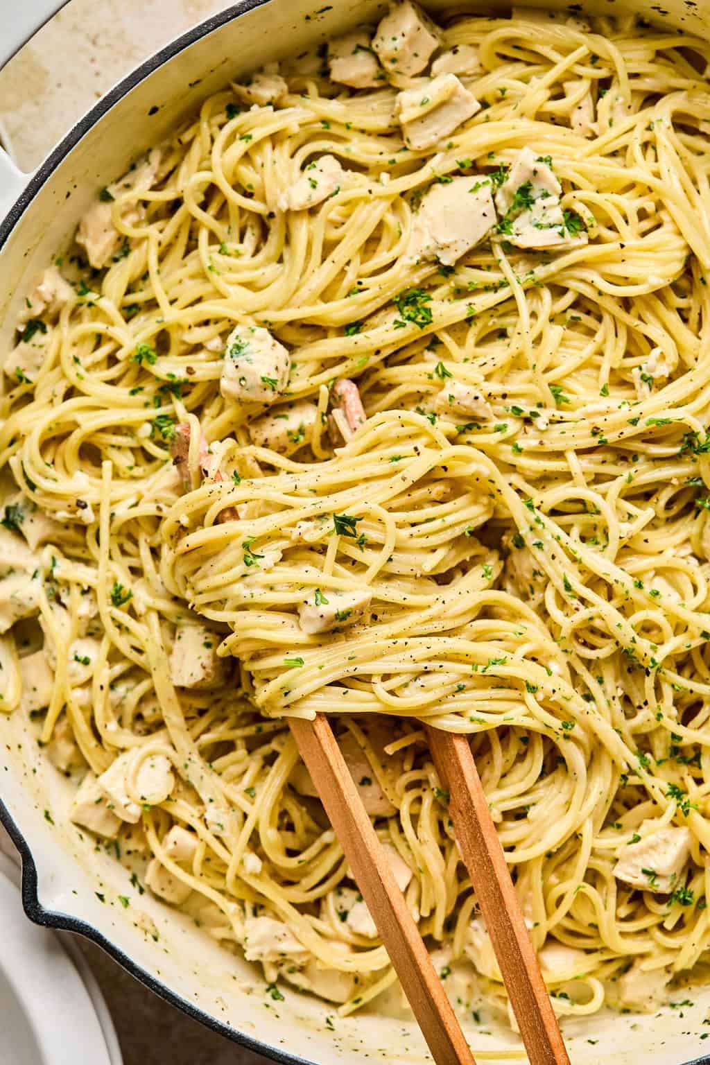 One pot easy chicken alfredo in pan with tongs wrapping pasta.