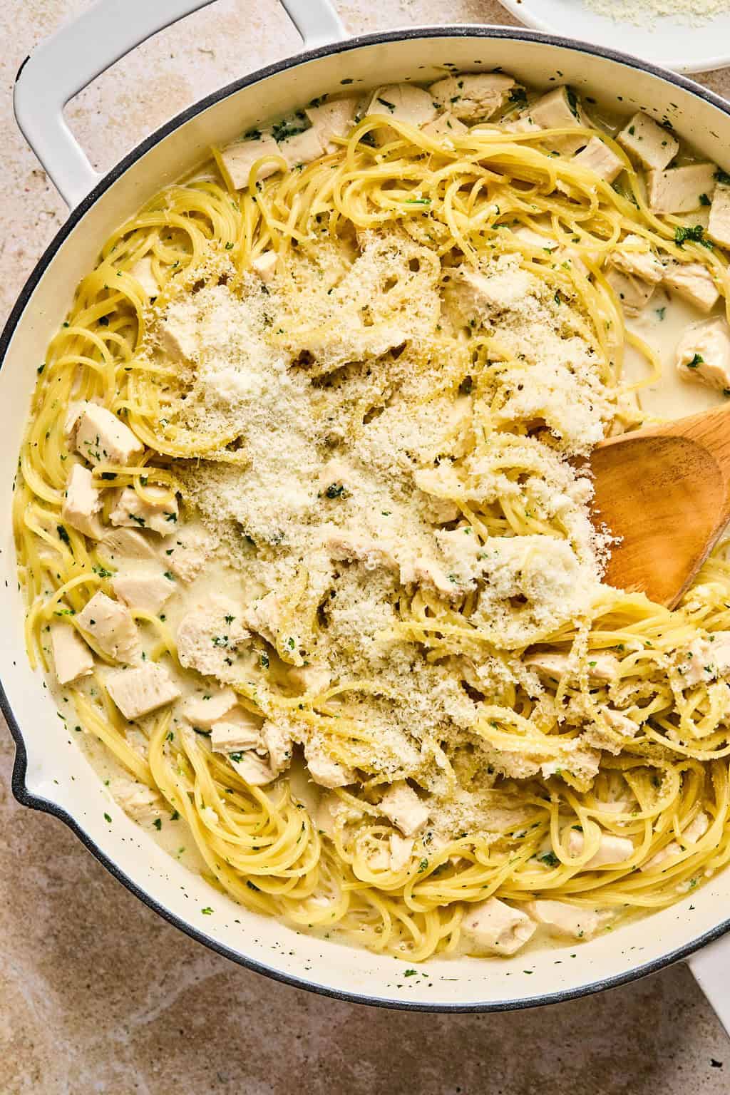 Parmesan added to pot with chicken alfredo.