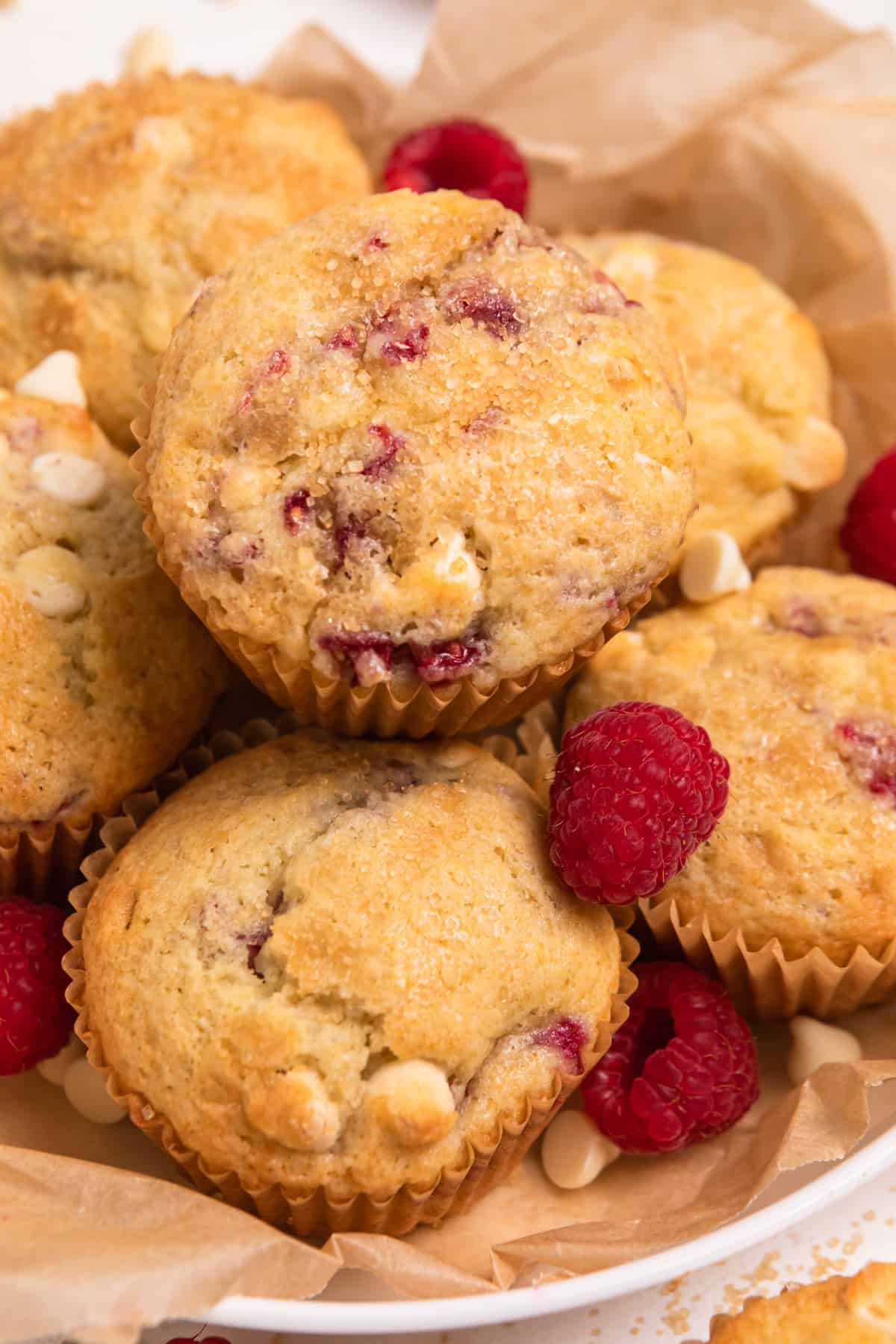 Bowl lined with parchment with white chocolate raspberry muffins.