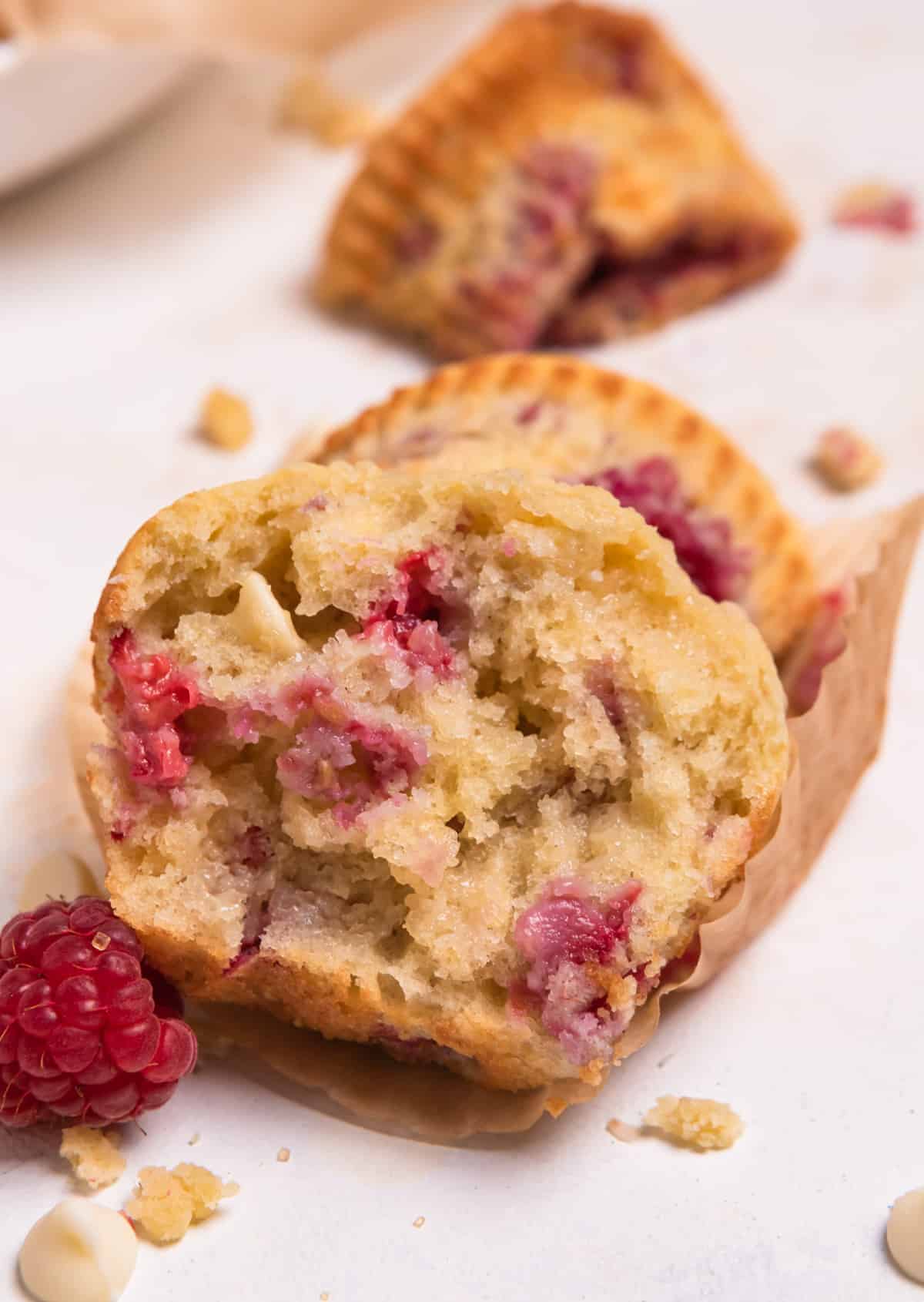 Sliced raspberry white chocolate muffin on wrapper.