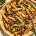 Plate with sun-dried tomato pasta topped with parmesan and chopped basil.
