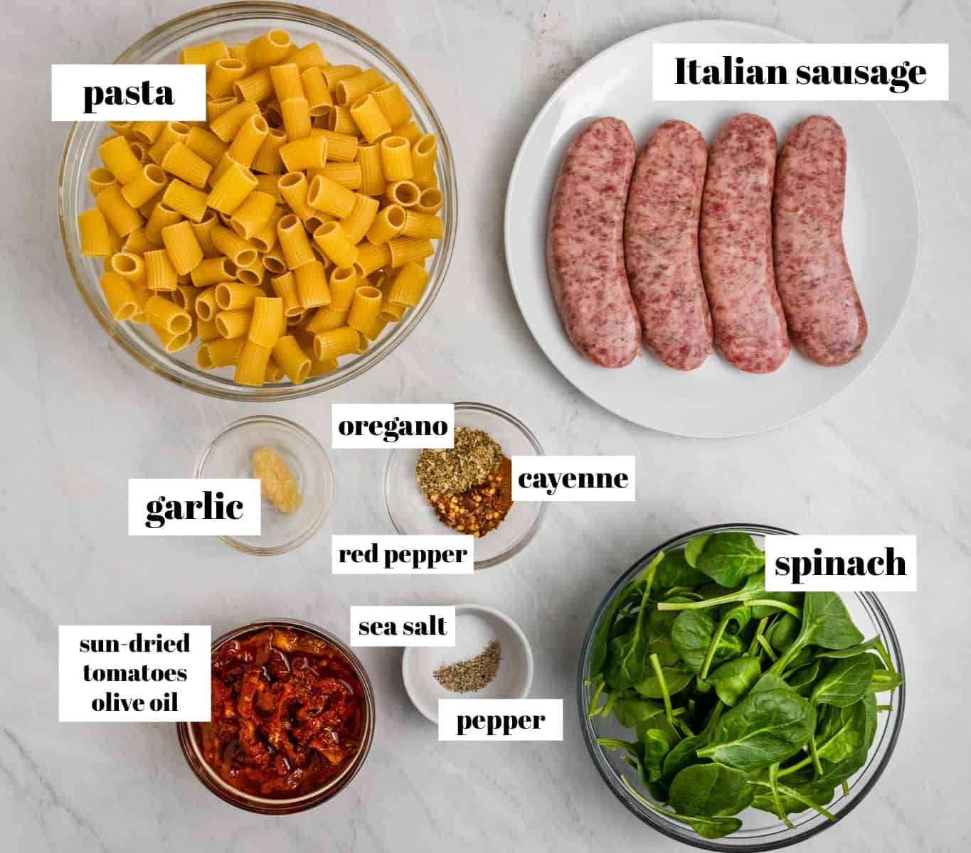 Rigatoni, spinach, garlic and other ingredients labeled on counter.