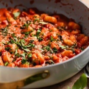Creamy tomato basil skillet gnocchi topped with chopped basil and parsley.