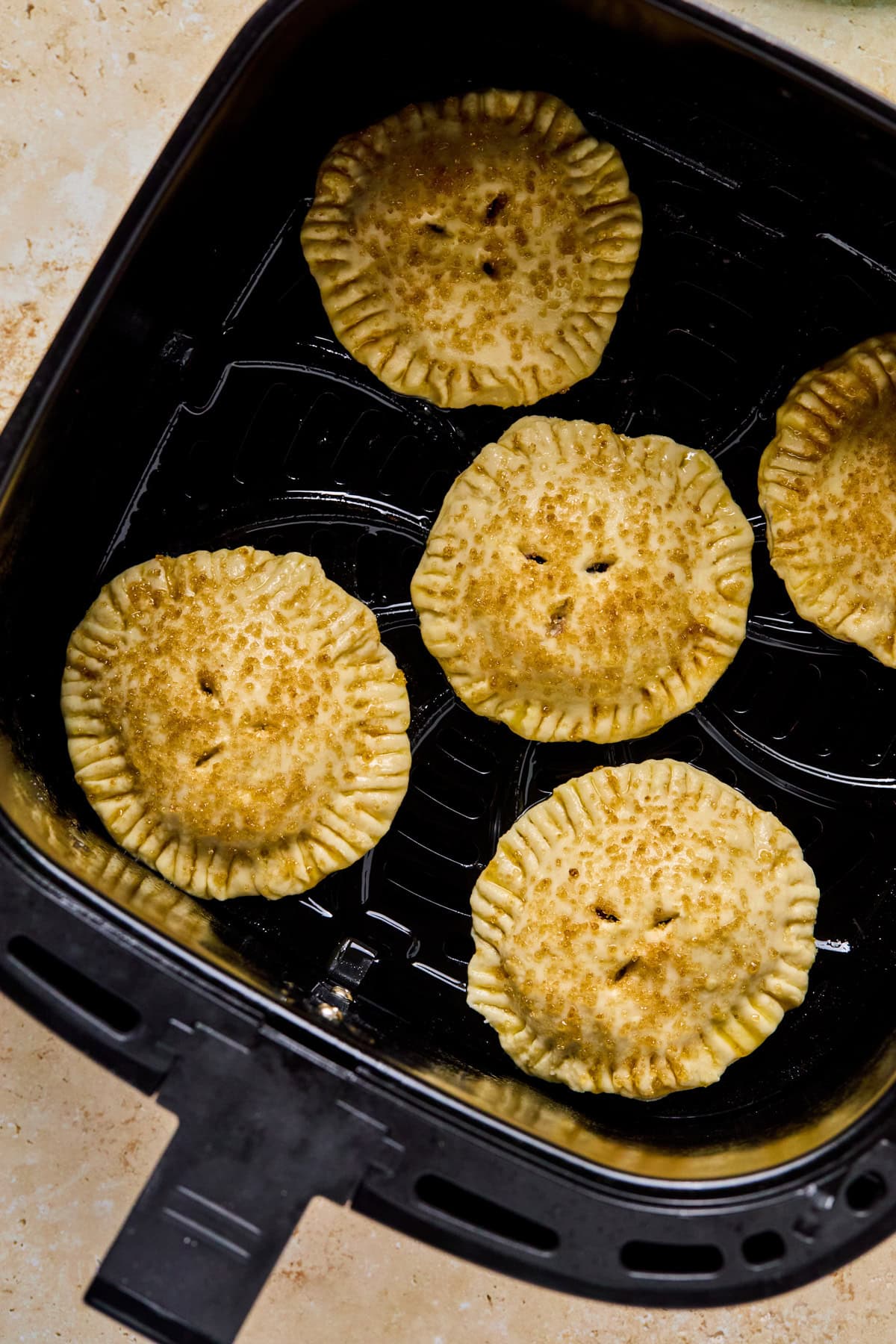 Air Fryer blue berry hand pies in air fryer basket before cooking.