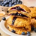 Stack of blueberry hand pies with top broken in half.