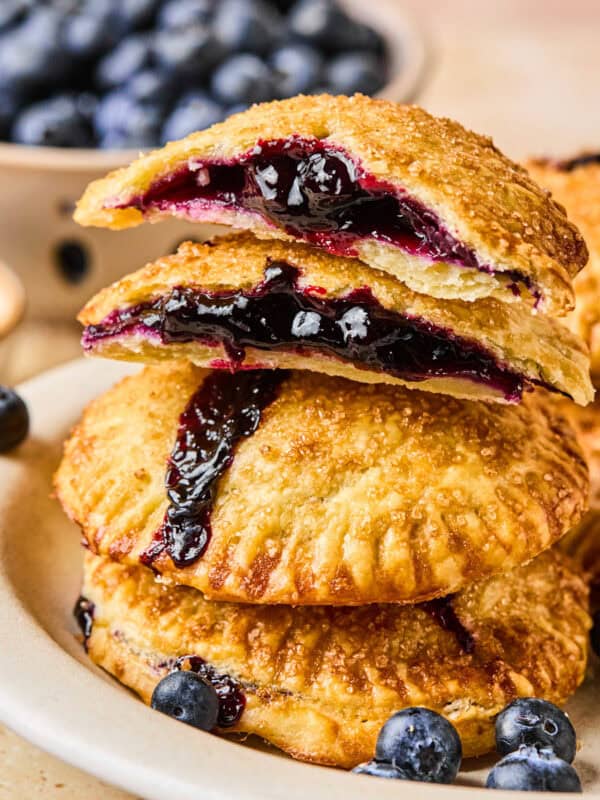Stack of blueberry hand pies with top broken in half.