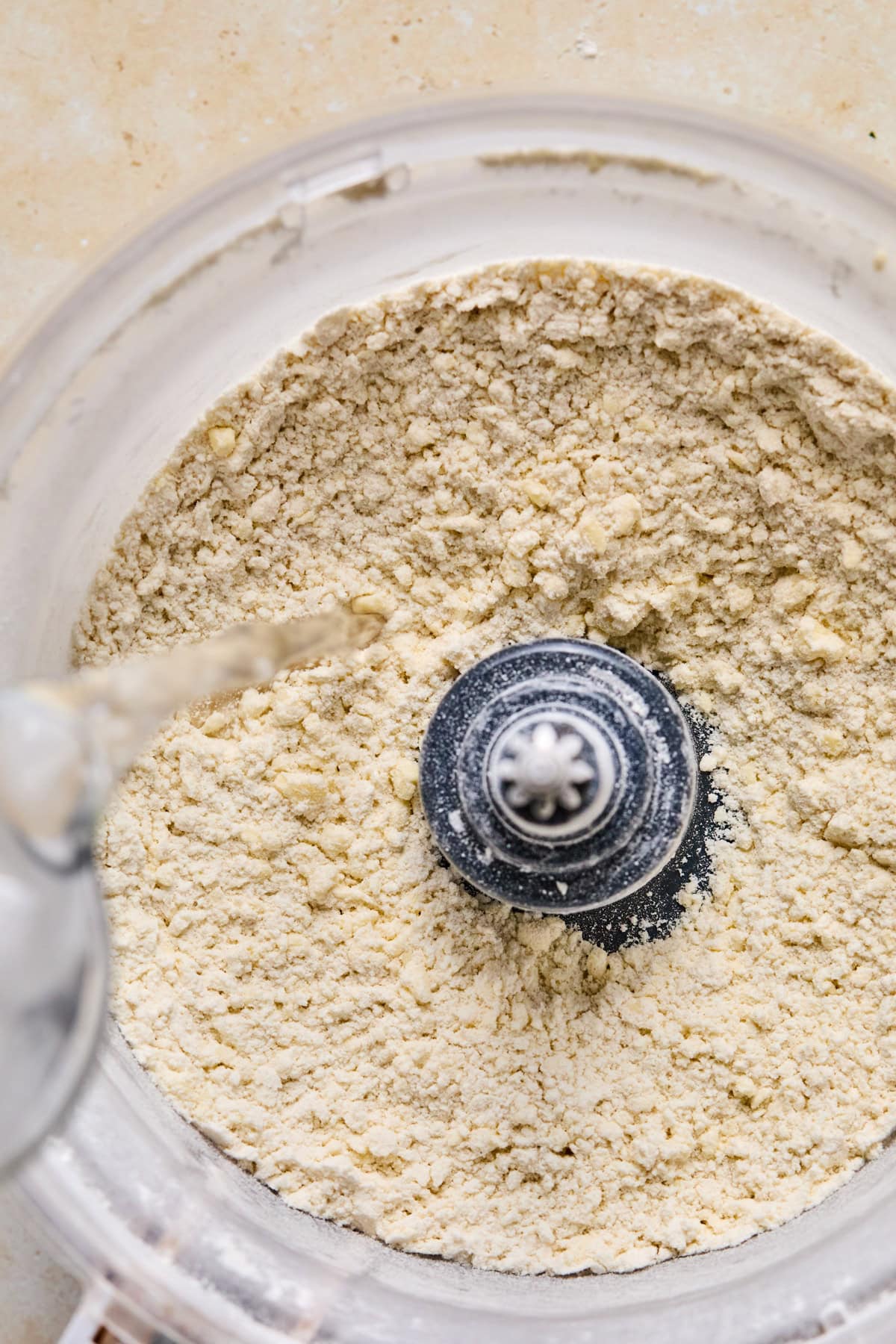 Water being poured into food processor with butter and flour mixture.
